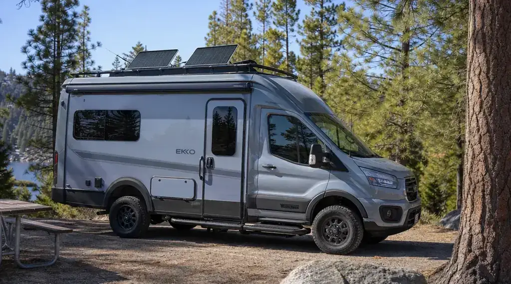 Solar panels on top of a parked RV under blue sky, battery bank powering the system